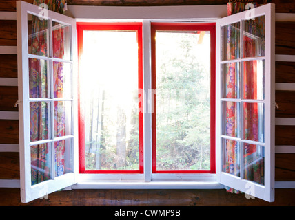 Aprire windows in cottage con sole e vista della foresta Foto Stock