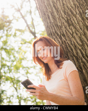 Stati Uniti d'America, New Jersey, Mendham, Donna appoggiata al tree e i messaggi di testo Foto Stock