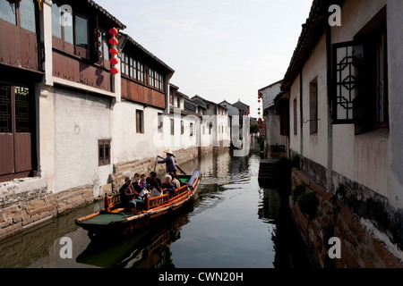 Un abitante di un villaggio righe una barca caricata con i turisti in un canale di Zhouzhuang città della provincia dello Jiangsu, Cina. Foto Stock