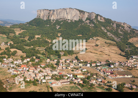 VISTA AEREA. Villaggio dominato da un monolito isolato. Pietra di Bismantova. Castelnovo ne' Monti, Provincia di Reggio Emilia, Emilia-Romagna, Italia. Foto Stock