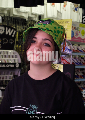 Teen girl cercando su un sciocco hat in un negozio di souvenir, Great Yarmouth, Norfolk, Regno Unito Foto Stock