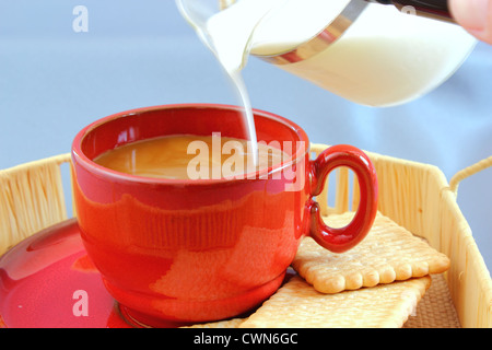 Mettere il latte proveniente da un recipiente di vetro nel caffè Foto Stock