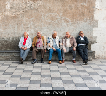 Anziani gli uomini italiani seduta su una panchina a Taormina, in Sicilia. Foto Stock