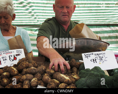 L'uomo vendita di patate sul mercato in stallo. Foto Stock