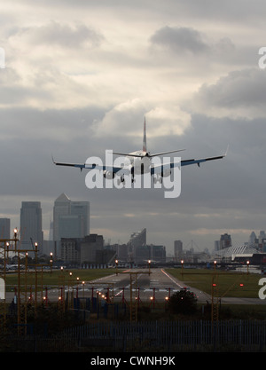 Viaggi aerei nel Regno Unito. L'aereo atterra all'aeroporto di Londra City, con la pista in vista e il quartiere finanziario visibile sullo sfondo. Foto Stock