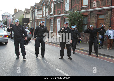 Gli ufficiali di polizia manganelli di richiamare durante l'Ala Destra EDL dimostrazione in Walthamstow Londra. Foto Stock