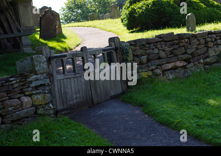 Vecchio artigianale in legno porta doppia, in tradizionali pietre a secco muro di pietra e attraverso un percorso che conduce al cimitero. Foto Stock