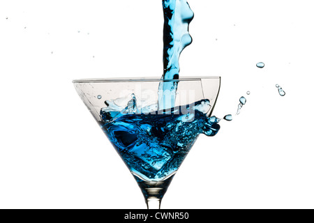 I cubetti di ghiaccio e martini di vetro riempita con il liquore blu su sfondo bianco Foto Stock