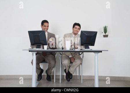 Imprenditori di mangiare fast food alla scrivania in ufficio Foto Stock