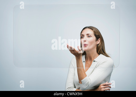 Donna soffia un bacio a grande schermo trasparente Foto Stock