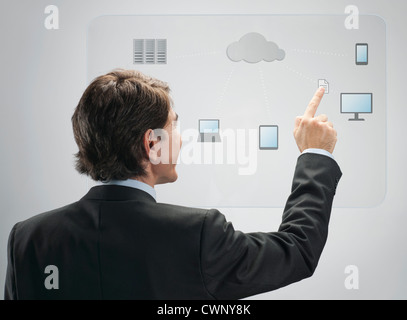 Imprenditore utilizzando la tecnologia di cloud computing su avanzate interfaccia touch-screen Foto Stock