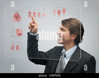 Imprenditore utilizzando l'avanzata tecnologia touch screen per visualizzare i dati delle vendite Foto Stock