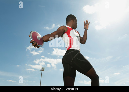 Atleta maschio gettando discus, basso angolo di visione Foto Stock