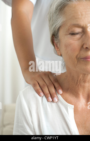 Senior donna ottenendo un massaggio della spalla, ritagliato Foto Stock