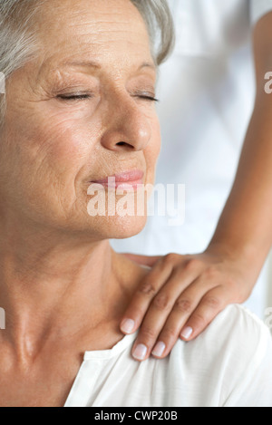 Senior donna ottenendo un massaggio della spalla, ritagliato Foto Stock