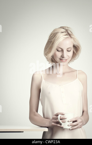 Giovane donna azienda tazza da caffè, ritratto Foto Stock
