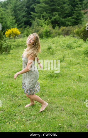 Giovane donna camminando sul prato con scalza Foto Stock