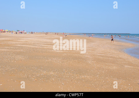 Vasta distesa di spiaggia di sabbia fine e dorata, vacanzieri in distanza, cielo blu, il caldo sole di mezzogiorno, Costa de la Luz. Foto Stock