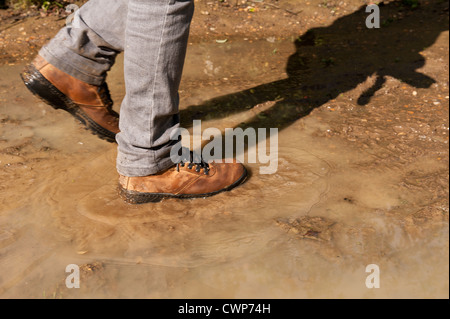 Rampicate spruzzi in una pozza camminando lungo il sentiero del fiume subito dopo la pioggia ha interrotto e sole esce tra le nuvole Foto Stock