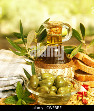 Olio d'oliva in bottiglia e fresco olive verdi in lastra di vetro sul tavolo, sana nutrizione organica, tradizionale cucina libanese Foto Stock