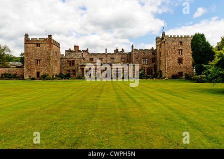 La storica facciata medievale di Muncaster Castle con le sue due torri merlate come si vede dal fondo del prato Foto Stock