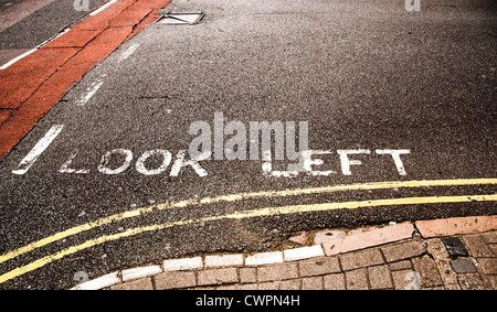 La segnaletica stradale avviso per guardare a sinistra prima di attraversare la strada Foto Stock