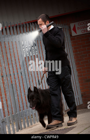 Una guardia di sicurezza e un pastore tedesco cane da guardia controllo sicurezza di notte su un trading station wagon Foto Stock
