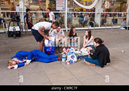 Giovani appassionati di musica al Festival della lettura si prendono una pausa per il pranzo al di fuori di un supermercato locale vicino al festival di musica sito. Foto Stock