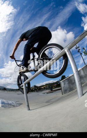 Biker facendo doppio peg smerigliare il corrimano su per le scale Foto Stock