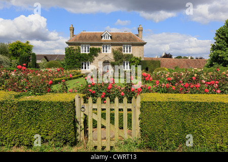 Hedge con gate al rose garden di fronte di un palazzo del XIX secolo la quintessenza Inglese country house in estate. Pluckley, Kent, Inghilterra, Regno Unito, Gran Bretagna Foto Stock