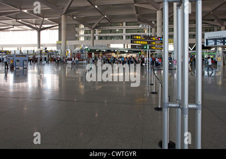 Un trafficato terminal aeroportuale concourse con code di passeggeri in background Foto Stock