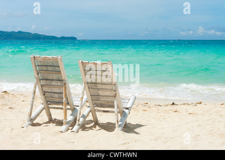 Spiaggia tropicale con due sedie a sdraio di fronte al mare blu Foto Stock