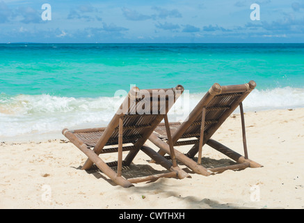 Spiaggia tropicale con due sedie a sdraio di fronte al mare blu Foto Stock