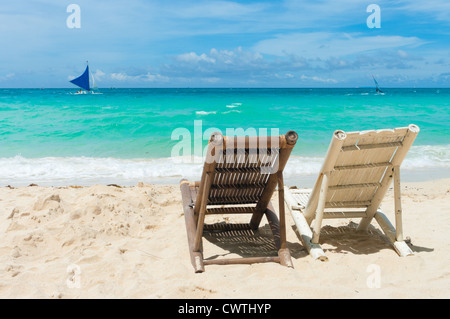 Spiaggia tropicale con due sedie a sdraio di fronte al mare blu Foto Stock