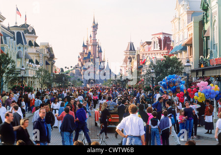 Il castello con la strada principale dei negozi, giostre e persone durante il giorno a Euro Disneyland a Euro Disney Resort al di fuori di Parigi Foto Stock