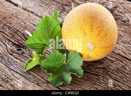 Il melone con le foglie sul vecchio tavolo in legno. Foto Stock