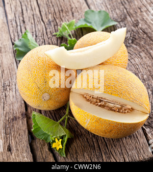 Il melone a fette e foglie su un vecchio tavolo di legno. Foto Stock