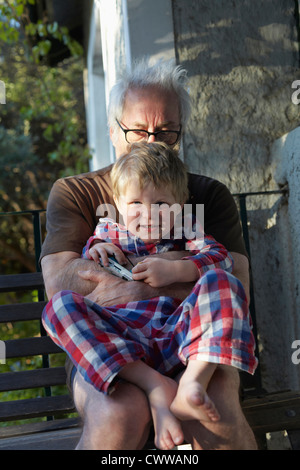 Uomo anziano abbracciando il nipote all'aperto Foto Stock