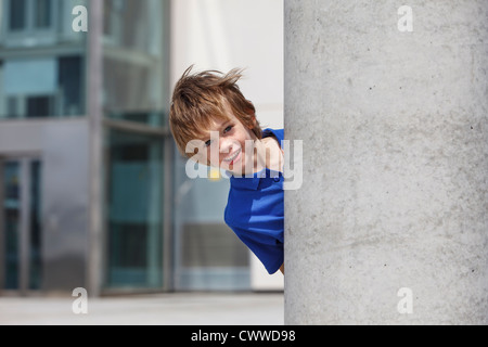 Ragazzo del peering fuori da dietro la colonna Foto Stock