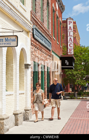 Un uomo e una donna camminare sul marciapiede davanti al salone del palazzo nel centro cittadino di Fernandina Beach in Amelia Island in Florida Foto Stock