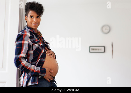 Donna incinta inclinazione nella porta Foto Stock
