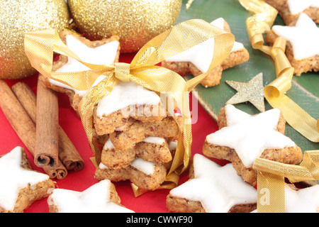 A forma di stella di Natale i cookie di cannella. Decorate con oro decorazioni natalizie e bastoncini di cannella. Foto Stock