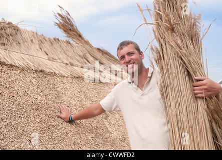 Uomo al lavoro su tetto di paglia Foto Stock