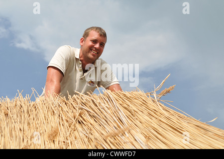 Uomo al lavoro su tetto di paglia Foto Stock