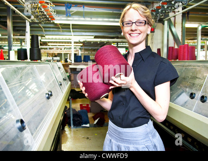 Lavoratore con bobine di filo in fabbrica Foto Stock