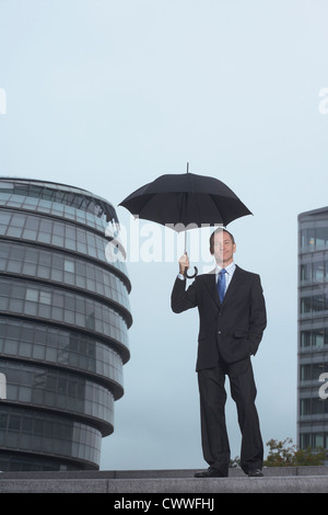 Imprenditore in piedi sotto ombrellone Foto Stock