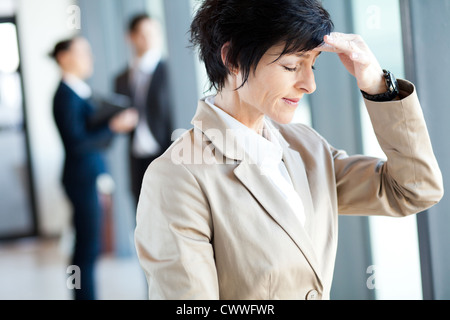 Persone di mezza età imprenditrice avente mal di testa in ufficio Foto Stock