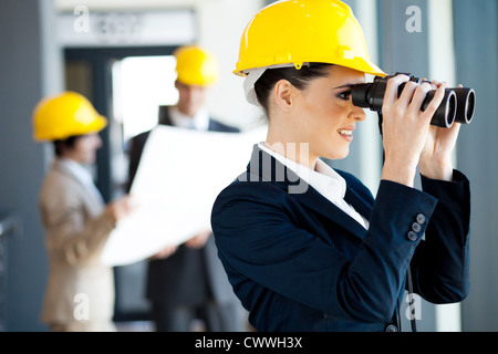 Giovani donne architetto guardando il sito in costruzione con il binocolo Foto Stock