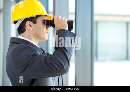 Architetto maschio guardando il sito in costruzione con il binocolo Foto Stock