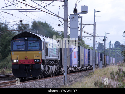 DRS classe liveried 66 locomotiva diesel trasporta un contenitore di treno sulla linea principale della costa occidentale vicino a Holme, a nord di Carnforth. Foto Stock